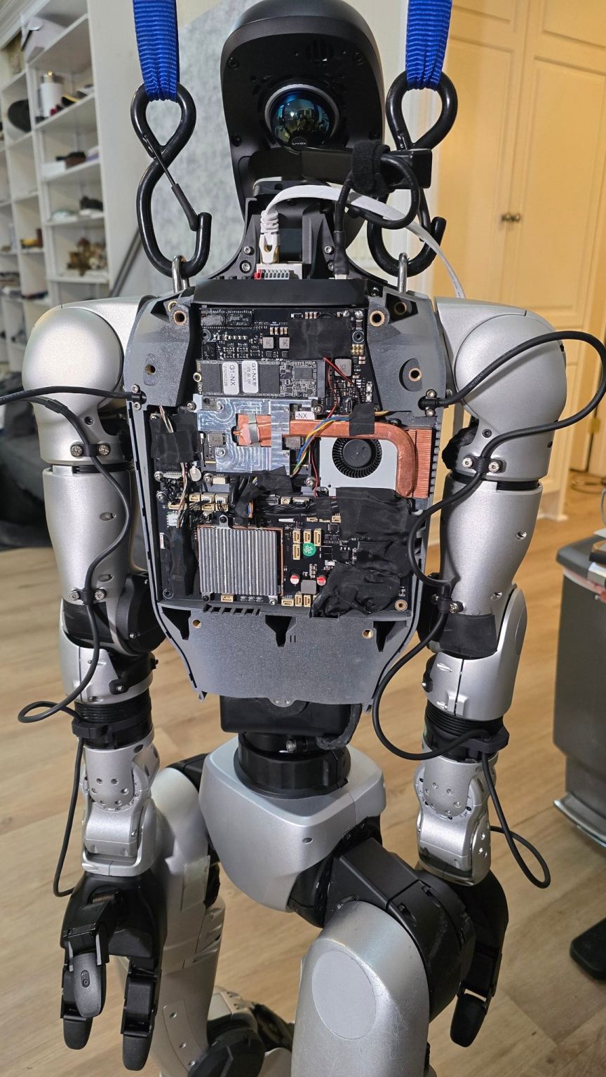 The open torso of a Unitree G1 humanoid robot showing its onboard computers, cooling system, wiring, and sensors